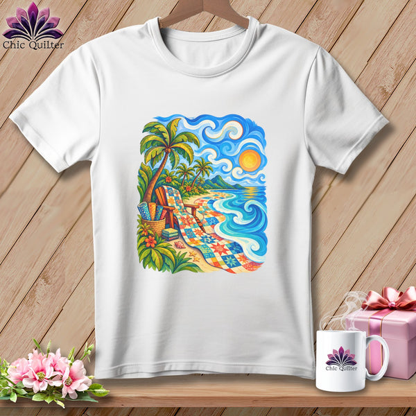 A white t-shirt featuring a colorful beach graphic with a patchwork quilt, palm trees, and ocean waves.