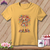 Gold t-shirt featuring a whimsical illustration of a girl holding folded fabric and surrounded by sewing notions.