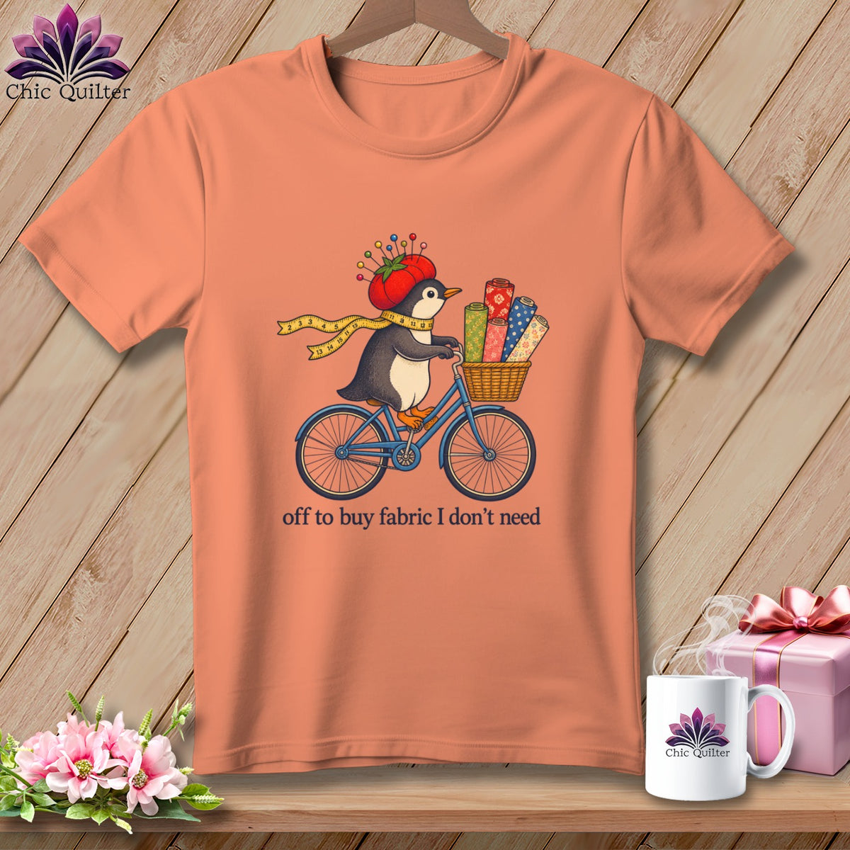 Penguin on bicycle with fabric rolls, wearing tomato hat, text "off to buy fabric I don't need".
