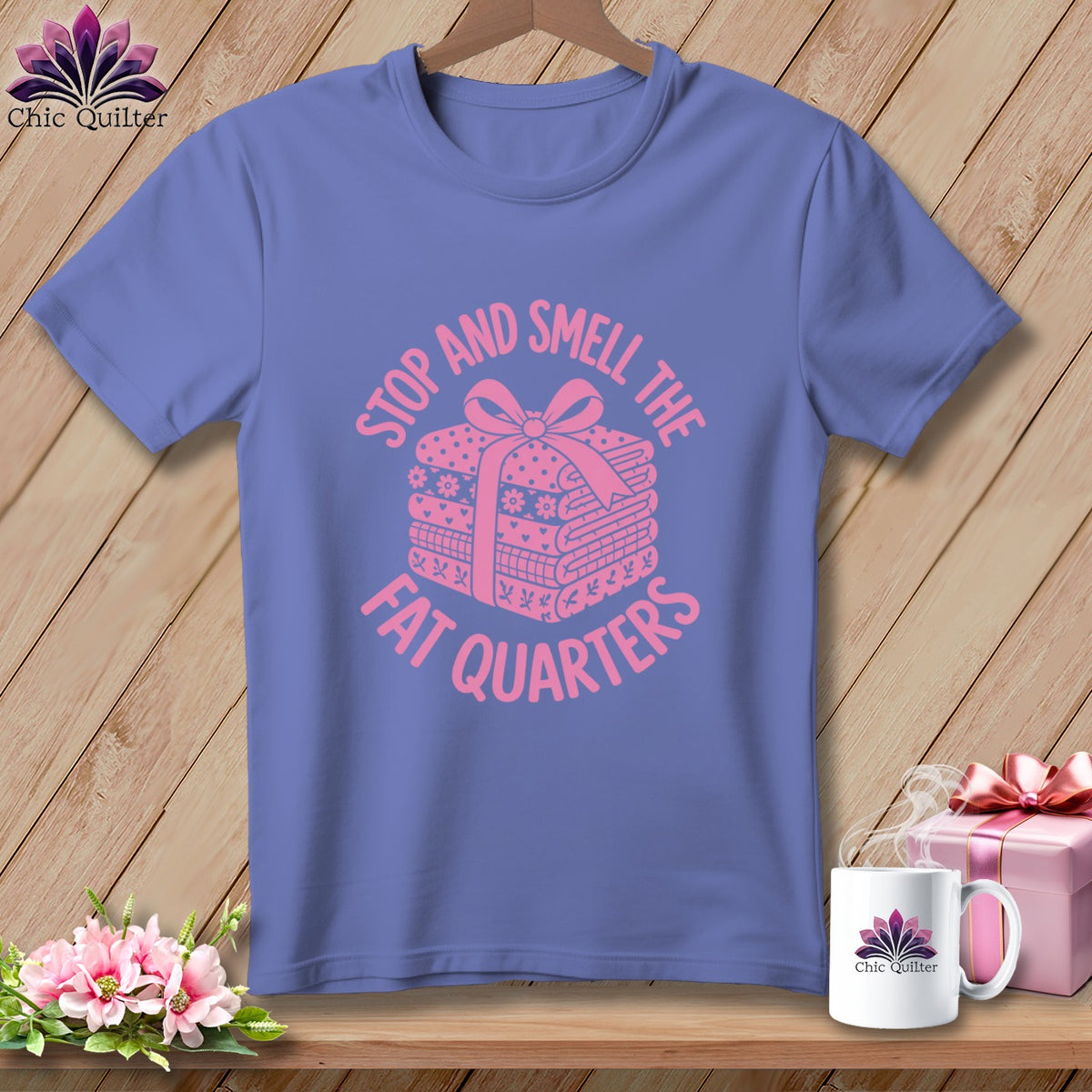 A blue t-shirt with pink text reading "STOP AND SMELL THE FAT QUARTERS" and a stack of fabric quarters tied with a bow.