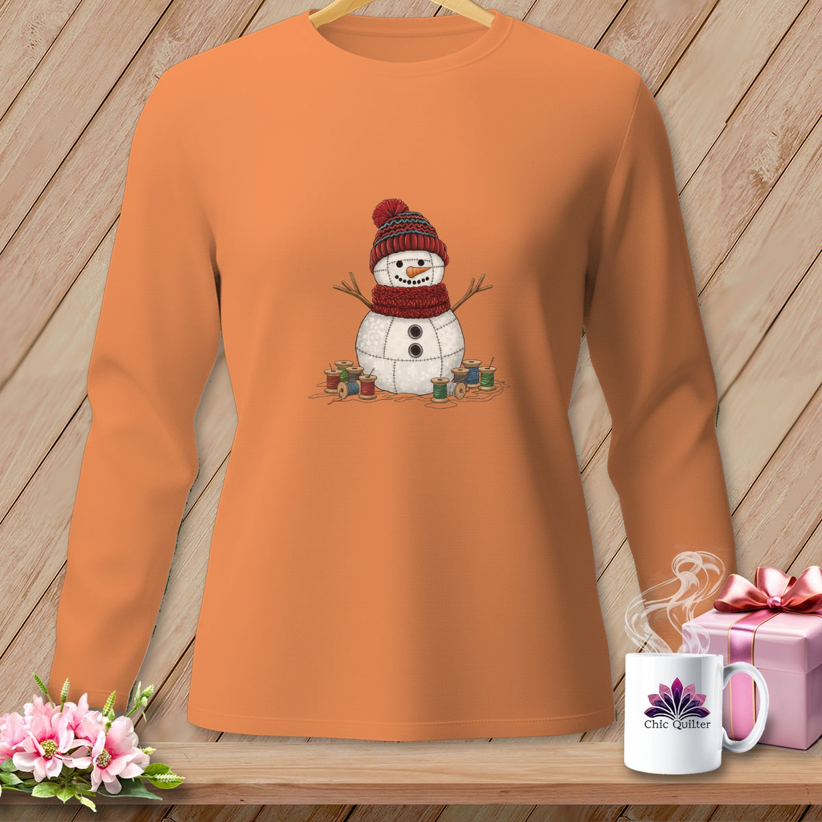 Orange long-sleeve shirt with a quilted snowman graphic and spools of thread.