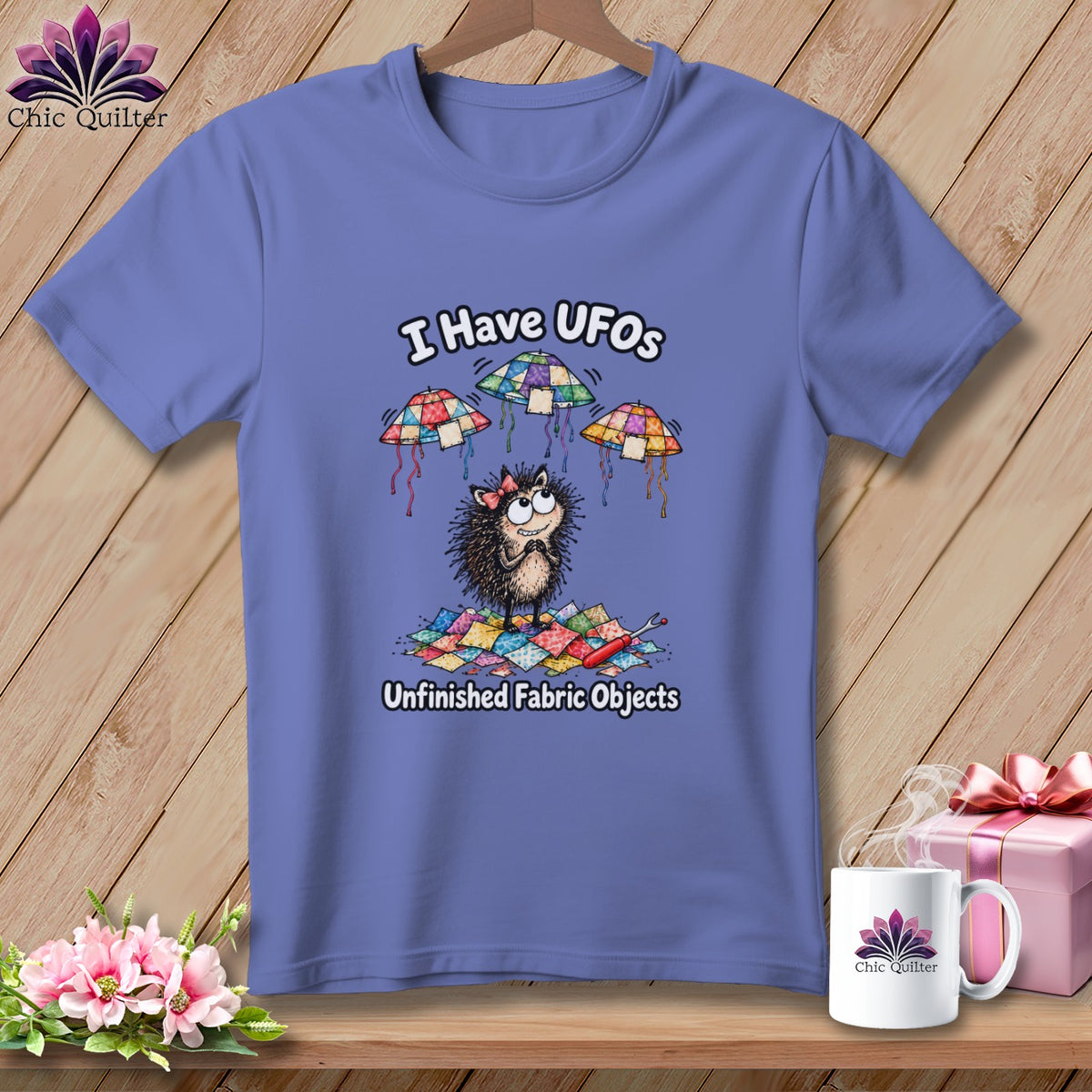 Periwinkle t-shirt featuring a cartoon hedgehog with quilt-block UFOs and the text "I Have UFOs Unfinished Fabric Objects".