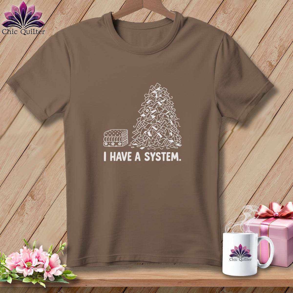 Brown t-shirt with white graphic of neat stacks and pile of fabric scraps saying "I HAVE A SYSTEM."