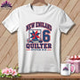 White short-sleeved t-shirt with a blue and red New England Quilter graphic on a wooden background.