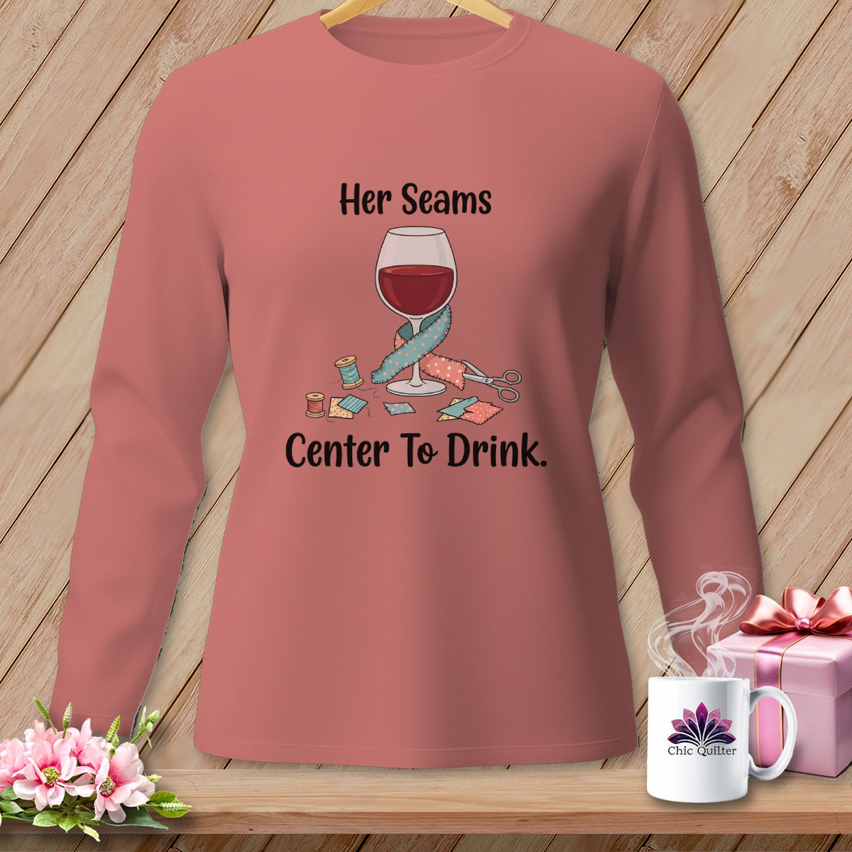 Pink long-sleeve shirt with graphic: wine glass, sewing notions, and text "Her Seams Center To Drink."