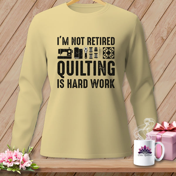 Beige sweatshirt with text "I'm Not Retired Quilting Is Hard Work" and sewing graphics.