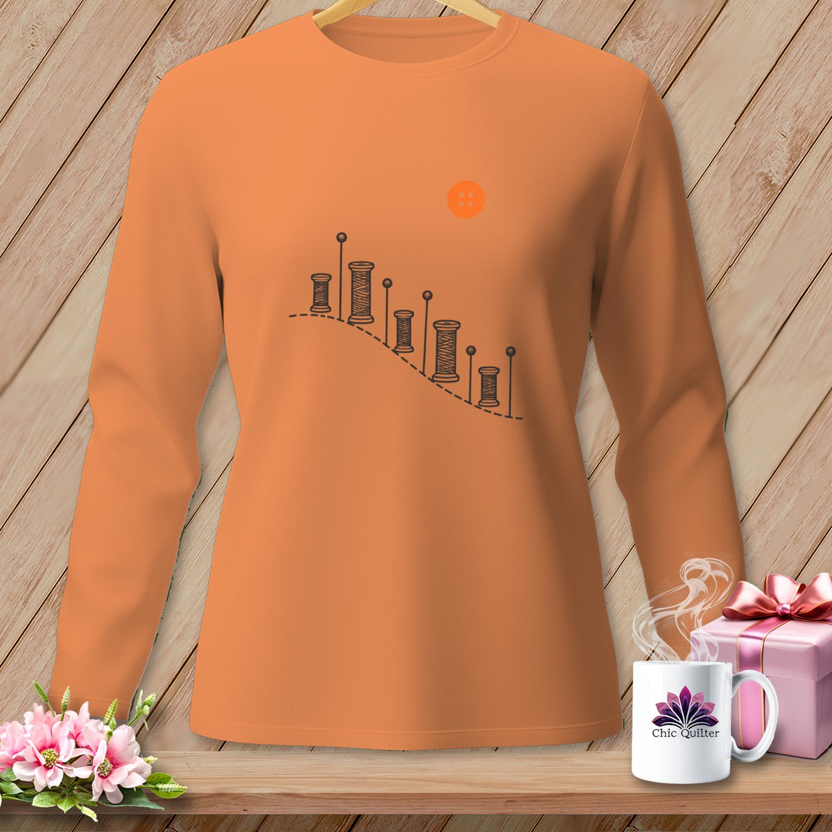 Orange long-sleeved shirt with spools of thread and buttons graphic.