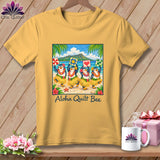 Yellow t-shirt hanging on a wooden background, featuring four hula-dancing penguins holding quilt blocks with the text Aloha Quilt Bee.