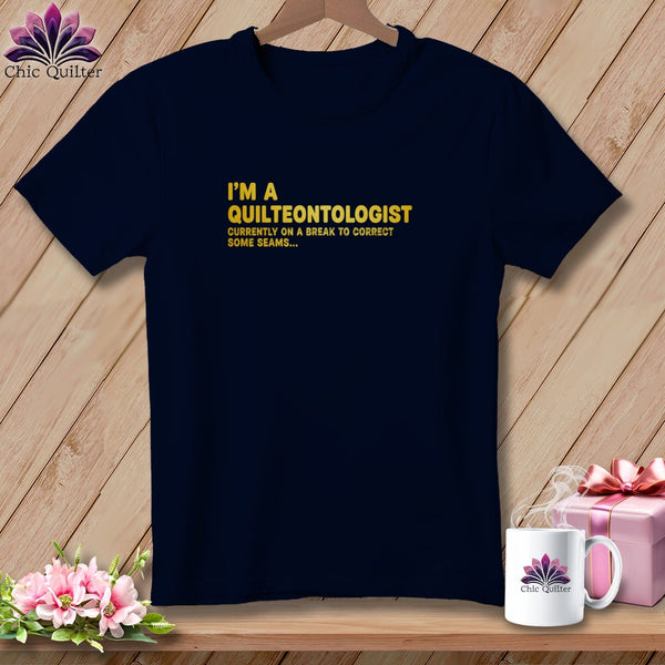 Navy t-shirt with yellow text: "I'M A QUILTEONTOLOGIST CURRENTLY ON A BREAK TO CORRECT SOME SEAMS..."