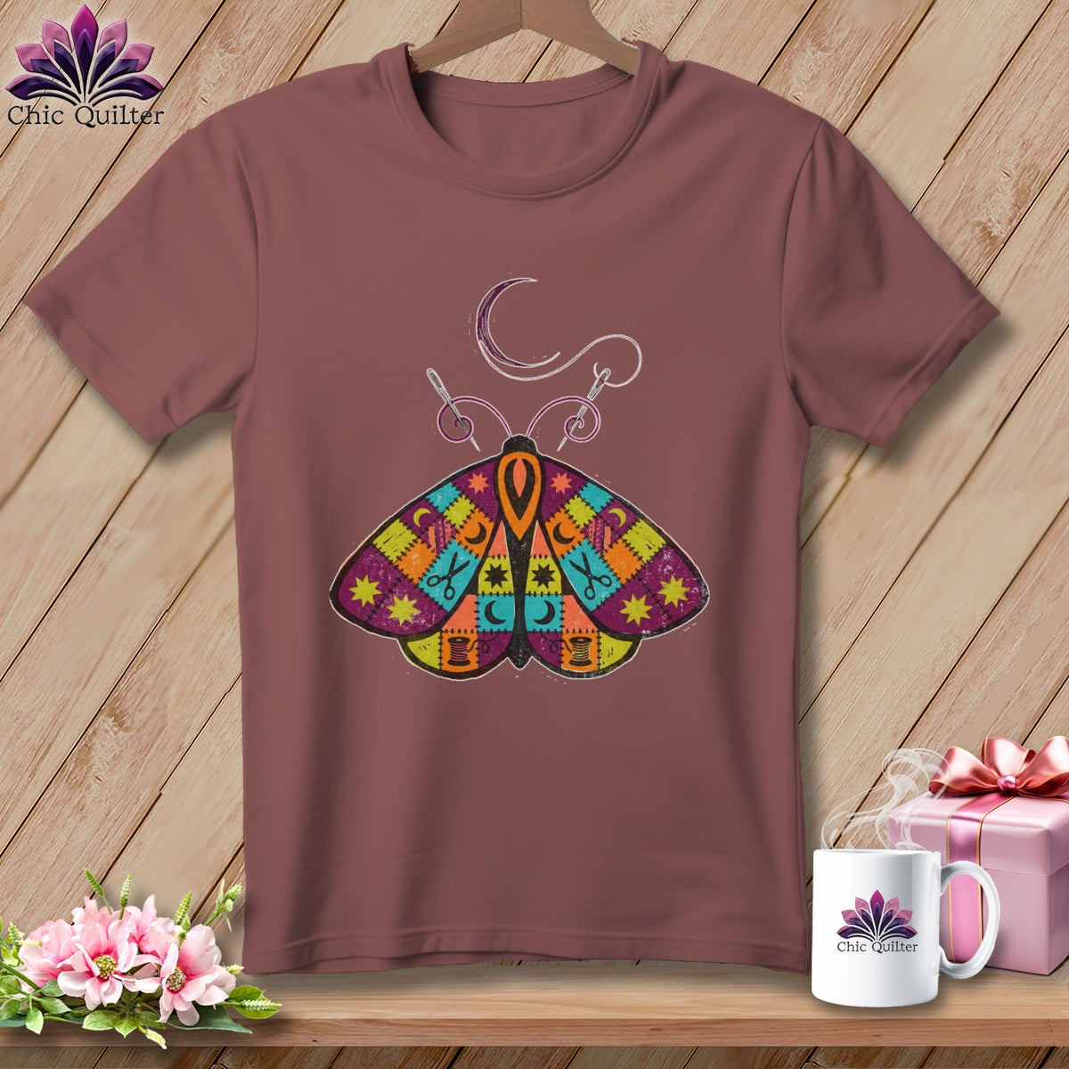 Brown t-shirt with colorful patchwork moth graphic, crescent moon, and sewing needle.