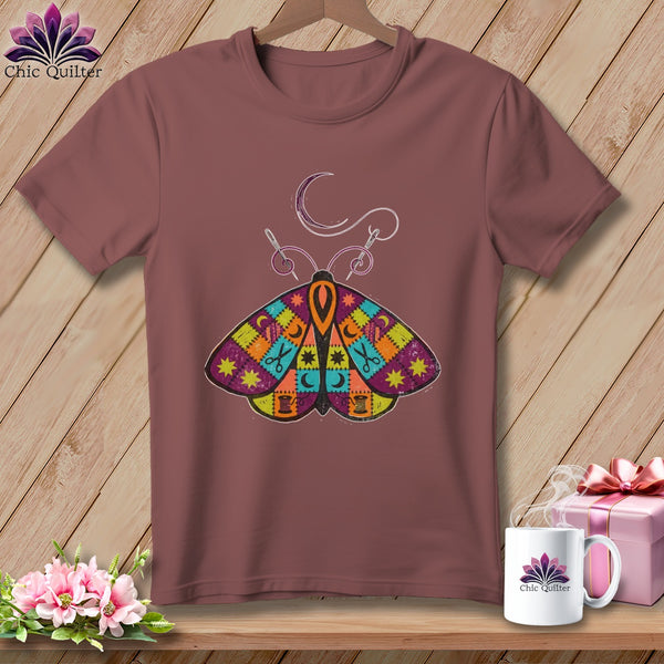 Brown t-shirt with colorful patchwork moth graphic, crescent moon, and sewing needle.
