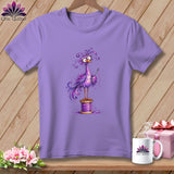 A purple short-sleeved t-shirt features a whimsical purple bird holding a needle while perched on a thread spool.