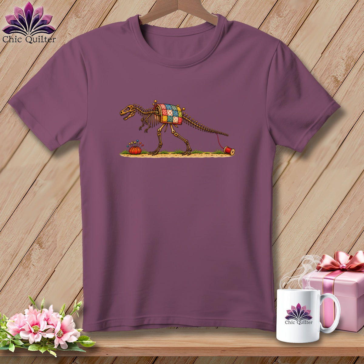 Purple t-shirt hanging on a wooden wall, featuring a dinosaur skeleton wearing a patchwork quilt.
