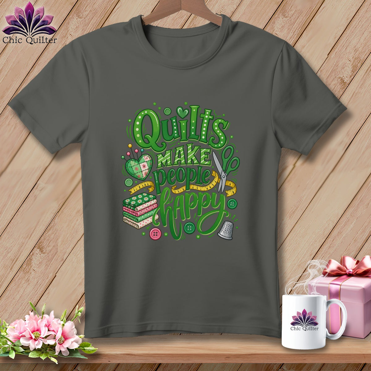 Charcoal gray t-shirt featuring green graphic text that reads Quilts Make People Happy with sewing-themed illustrations.