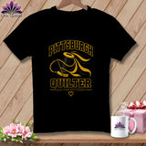 Black t-shirt featuring a yellow and black graphic of a spool of thread, needle, and text reading 