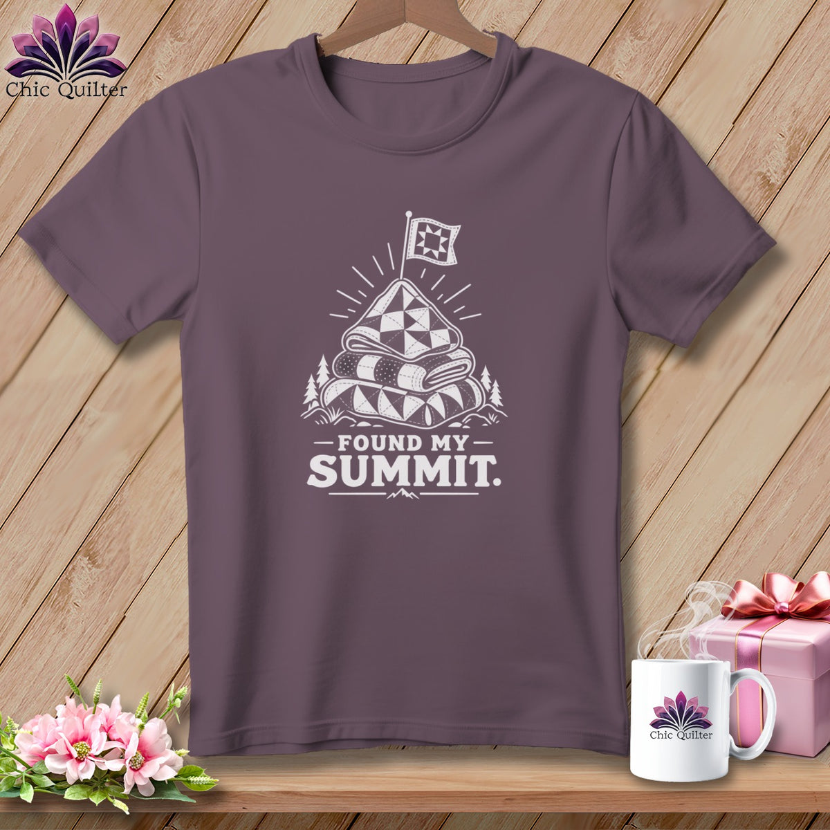 Purple t-shirt with a graphic of a stacked quilt on a mountain with a flag and text "Found My Summit."