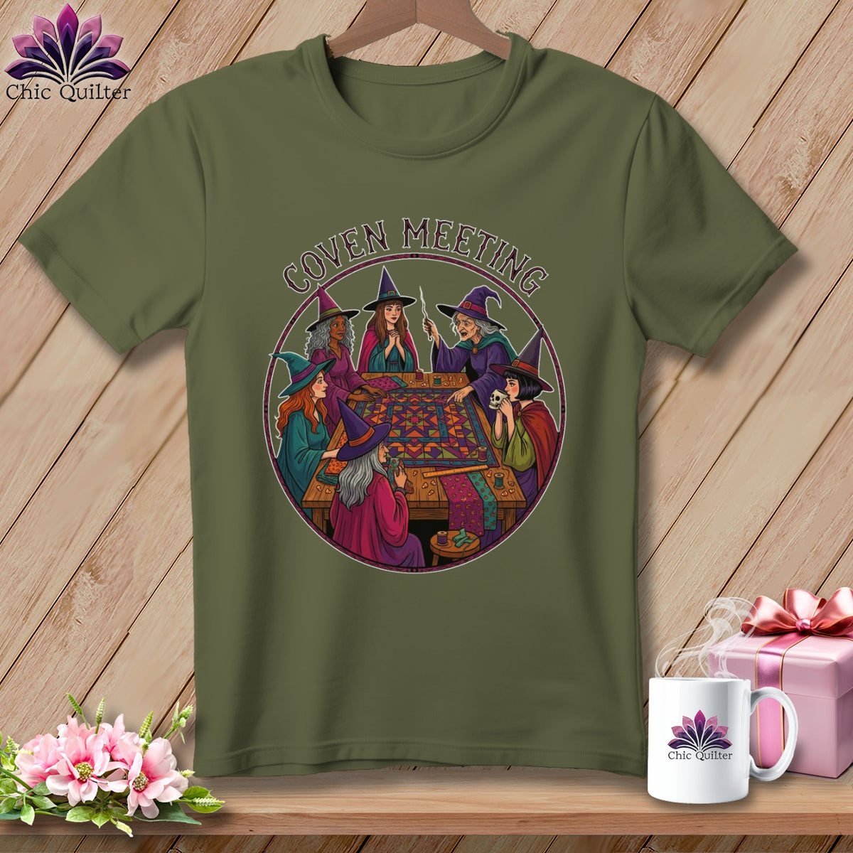 Olive green t-shirt with "Coven Meeting" text and illustrated witches quilting around a table.