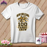 A white t-shirt features a black and yellow New Orleans Fabric Crew design on a wooden background.