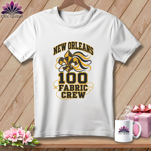 A white t-shirt features a black and yellow New Orleans Fabric Crew design on a wooden background.