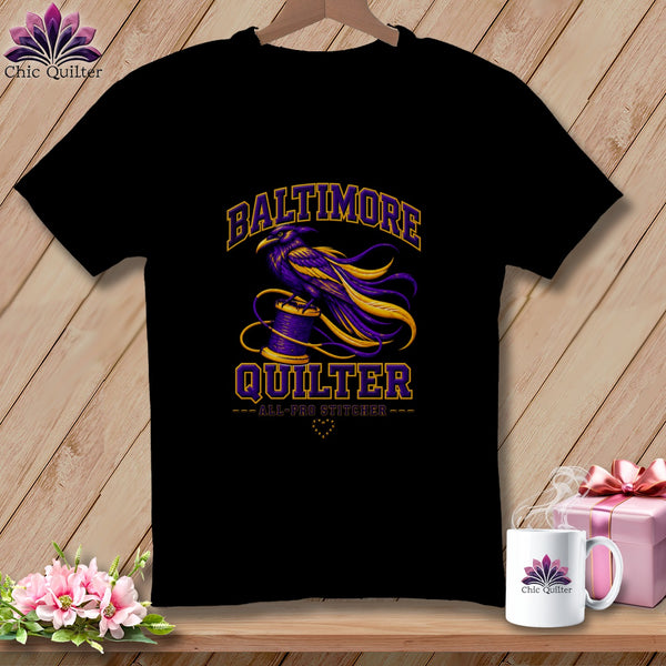 A black t-shirt features a purple and gold graphic of a raven perched on a spool of thread with text that reads Baltimore Quilter.