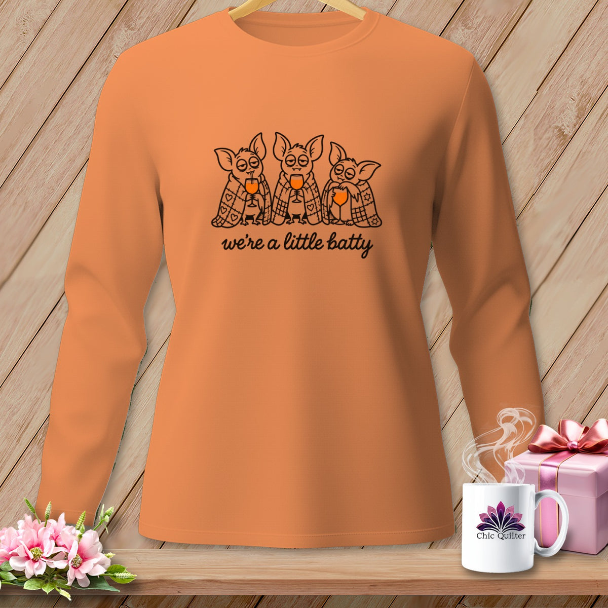 Orange long-sleeve shirt with bats drinking wine and text "we're a little batty".