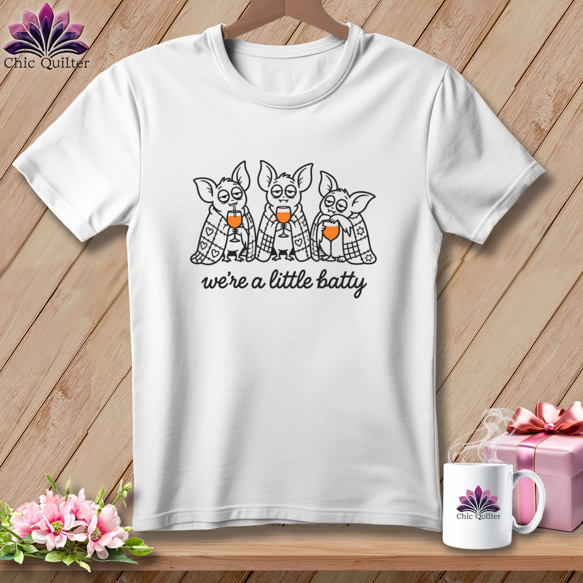 White t-shirt with three cartoon bats drinking from wine glasses, text "we're a little batty".