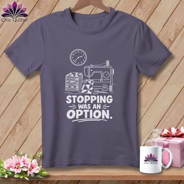 T-shirt with sewing machine, stacked fabric, clock, and text "Stopping was an option."
