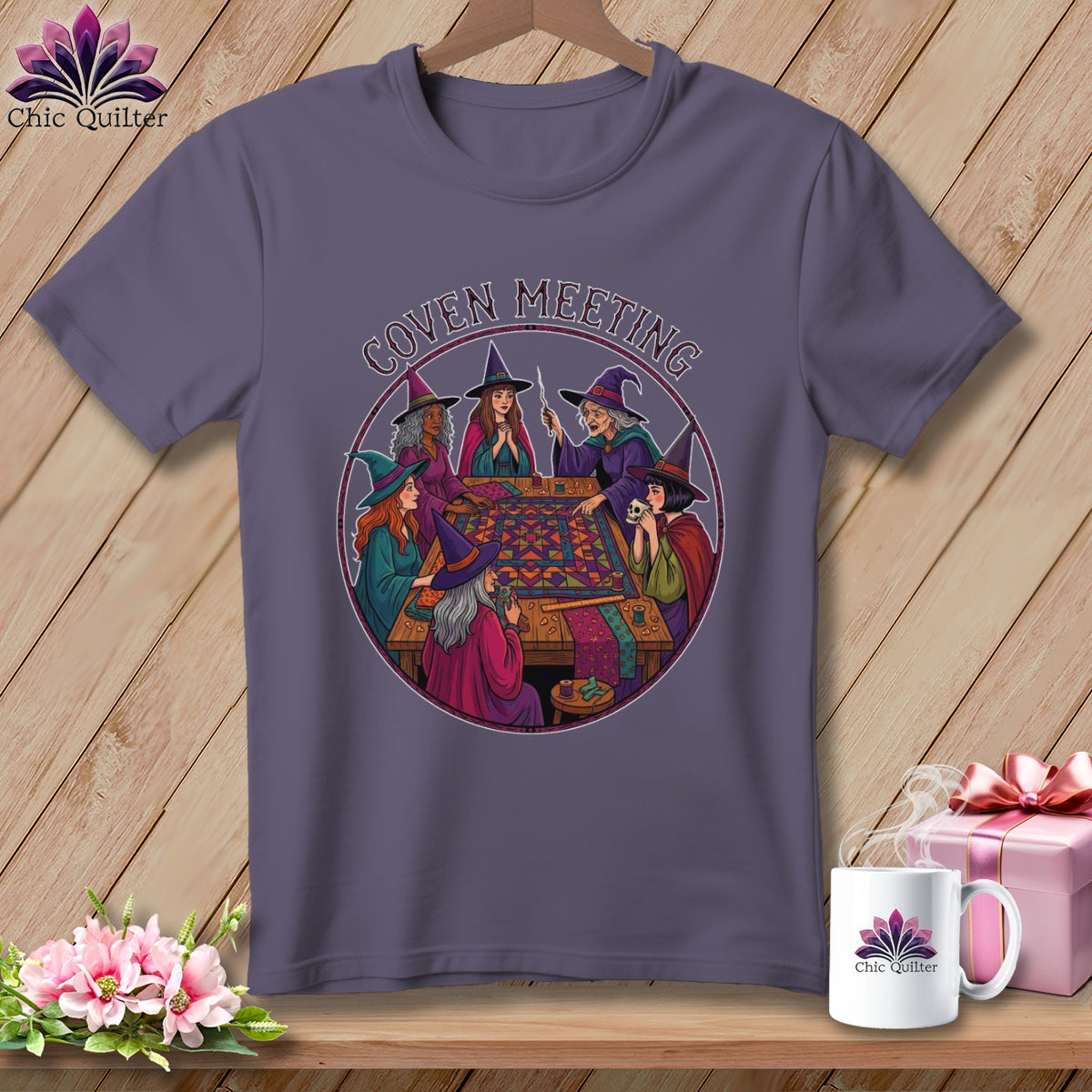 T-shirt with witches gathered around a quilt, text reads "Coven Meeting".