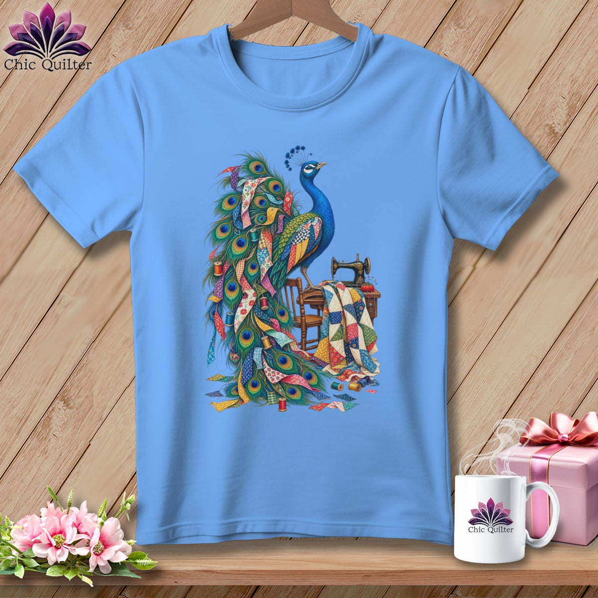 Light blue t-shirt with a peacock and quilting supplies graphic.