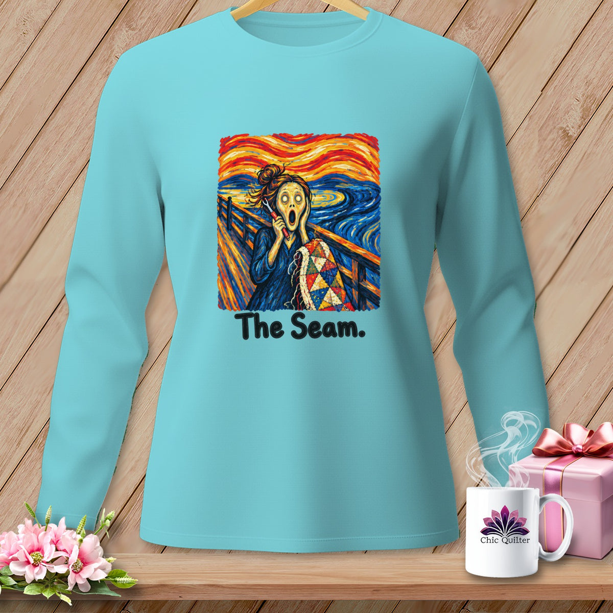 Aqua long sleeve shirt with "The Seam" graphic featuring a screaming figure holding a quilt.