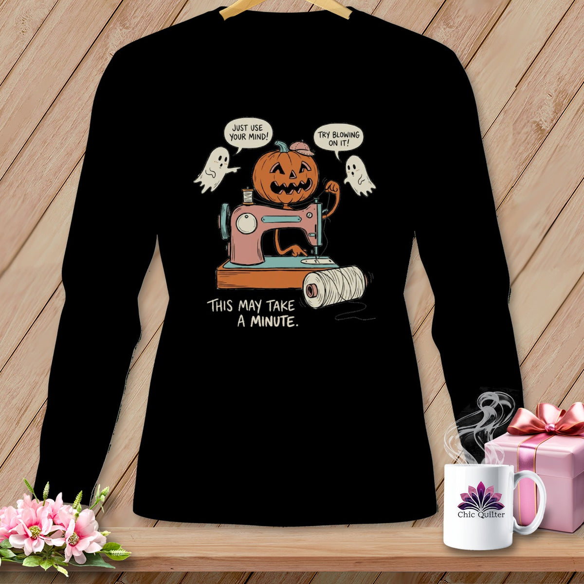 Black t-shirt with cartoon of jack-o-lantern sewing with ghosts, "This May Take A Minute."