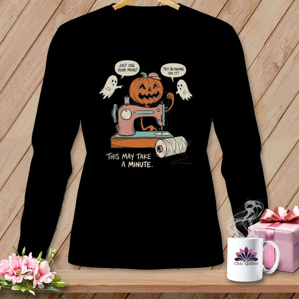 Black t-shirt with cartoon of jack-o-lantern sewing with ghosts, "This May Take A Minute."