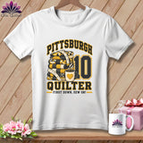 A white t-shirt features a graphic with the text Pittsburgh Quilter, a stack of quilts, a coffee mug, and the number 10.