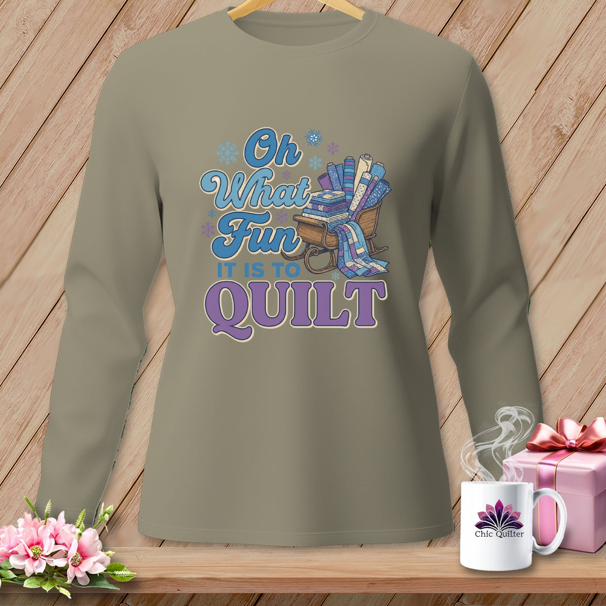 Long sleeve shirt with "Oh What Fun It Is To Quilt" graphic and sleigh of fabric rolls.