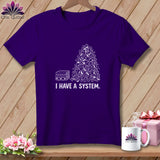 Purple t-shirt with a white graphic of a pile of fabric scraps and a stack of folded fabric.