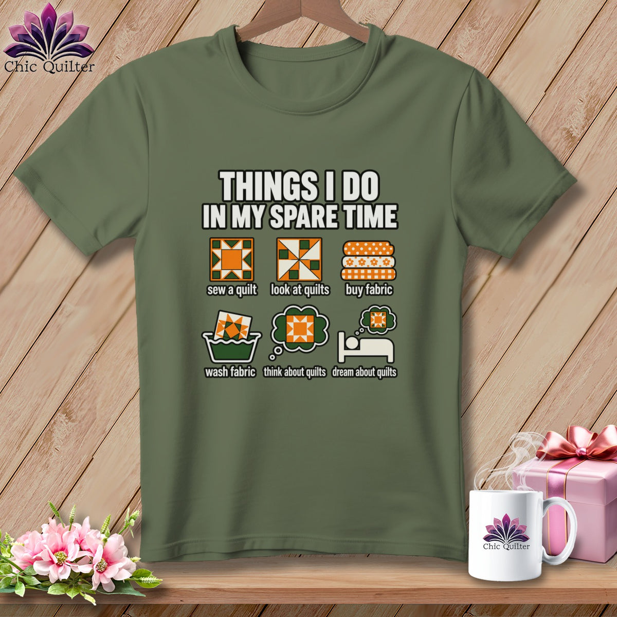 An olive green t-shirt with white text and illustrations about quilting displayed on a wooden background.