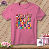 Pink t-shirt with a graphic of cartoon farm animals peeking over a colorful patchwork quilt.
