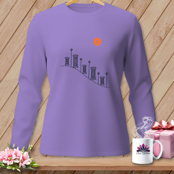 Purple long-sleeve shirt with thread spools and button graphic.