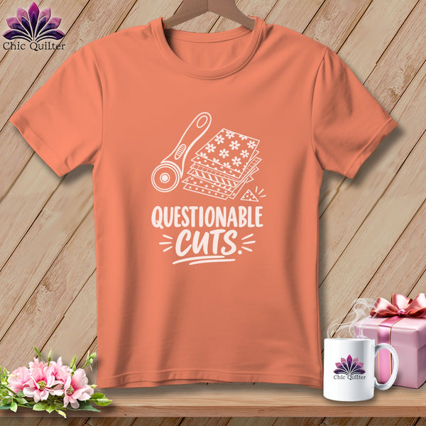 Peach t-shirt with white graphic of rotary cutter and fabric, reading "Questionable Cuts."