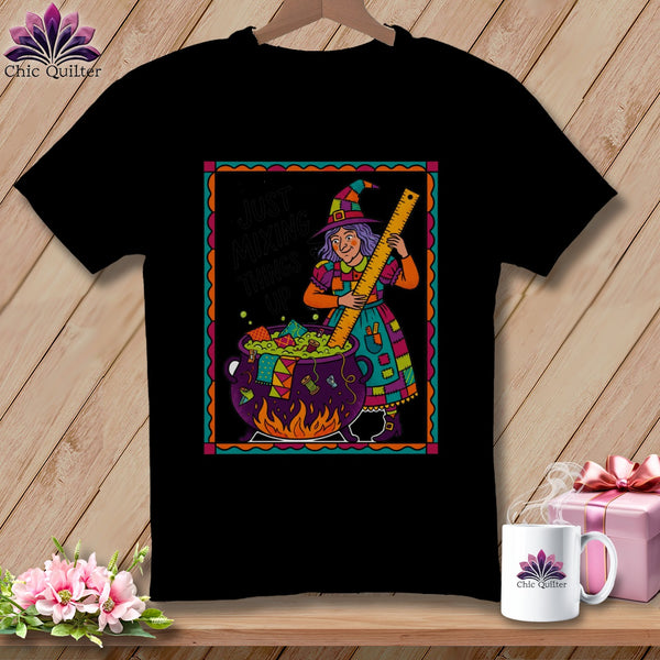Black t-shirt with witch and cauldron graphic reading "Just Mixing Things Up".