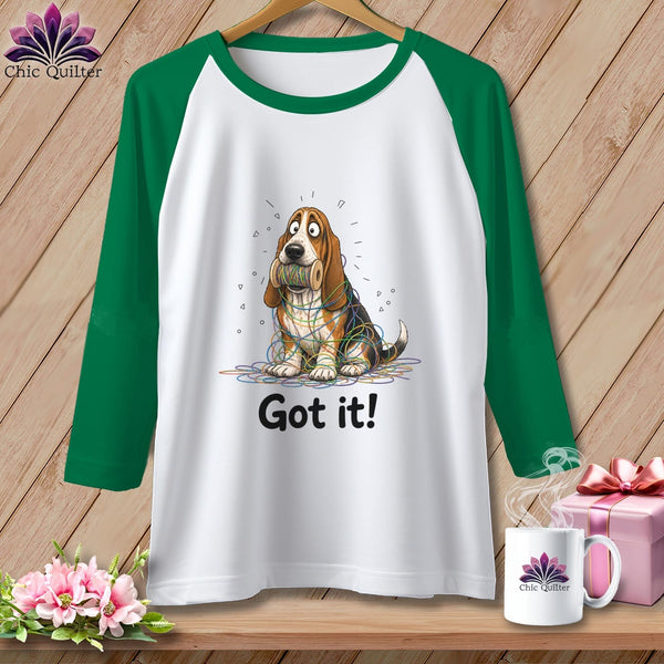 White raglan shirt with green sleeves featuring a basset hound tangled in yarn and the text "Got it!".