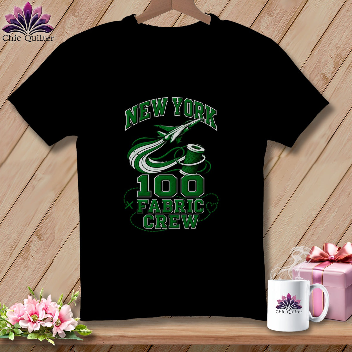 A black t-shirt hanging on a wooden background, featuring green text reading "NEW YORK 100 FABRIC CREW" with an airplane and spool graphic.
