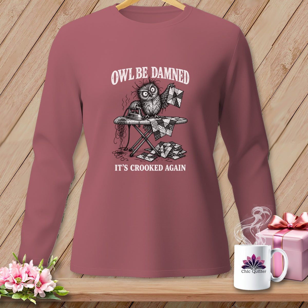 Long-sleeve shirt with a cartoon owl ironing a quilt, text reads "Owl Be Damned. It's Crooked Again."