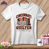 White t-shirt with a graphic of fabric rolls in a crate and text reading Cincinnati Quilter.