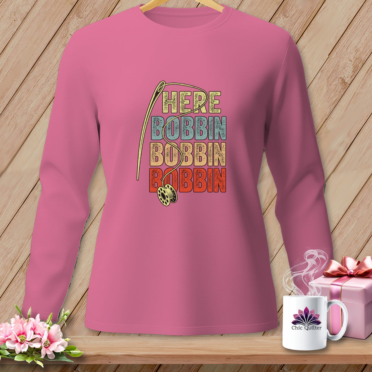 Pink long-sleeve shirt with needle, bobbin, and "HERE BOBBIN" text.