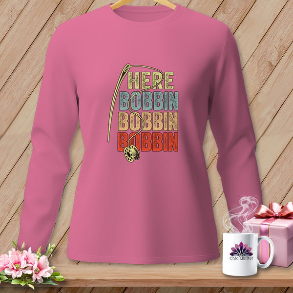 Pink long-sleeve shirt with needle, bobbin, and "HERE BOBBIN" text.