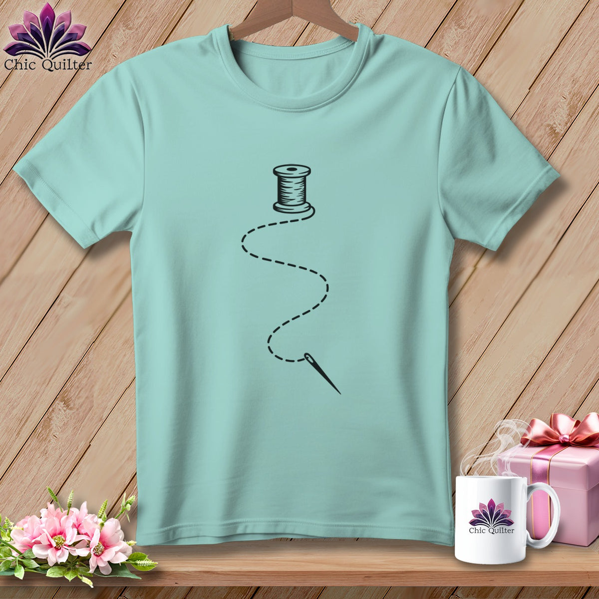Light blue t-shirt with black spool of thread and needle graphic.