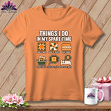 Orange t-shirt featuring quilting-themed illustrations and text about spare-time activities, displayed against a wooden background.