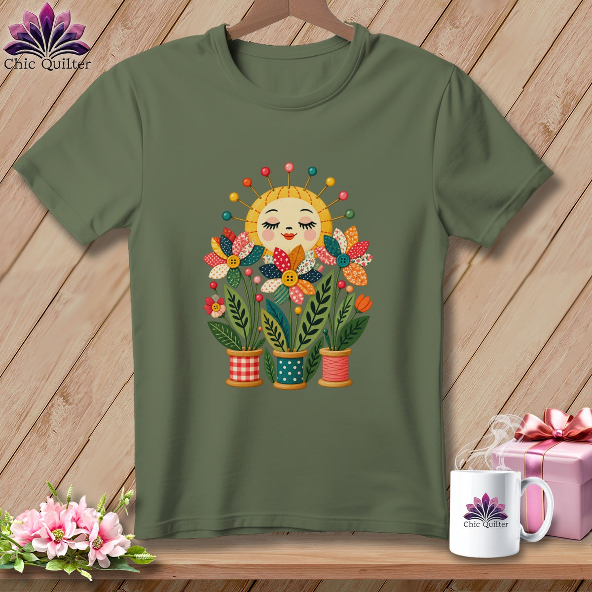 An olive green t-shirt featuring a colorful graphic of patchwork flowers and a smiling sun with pins.
