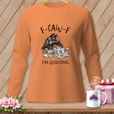Orange long-sleeve shirt with a crow sewing a quilt and the text 